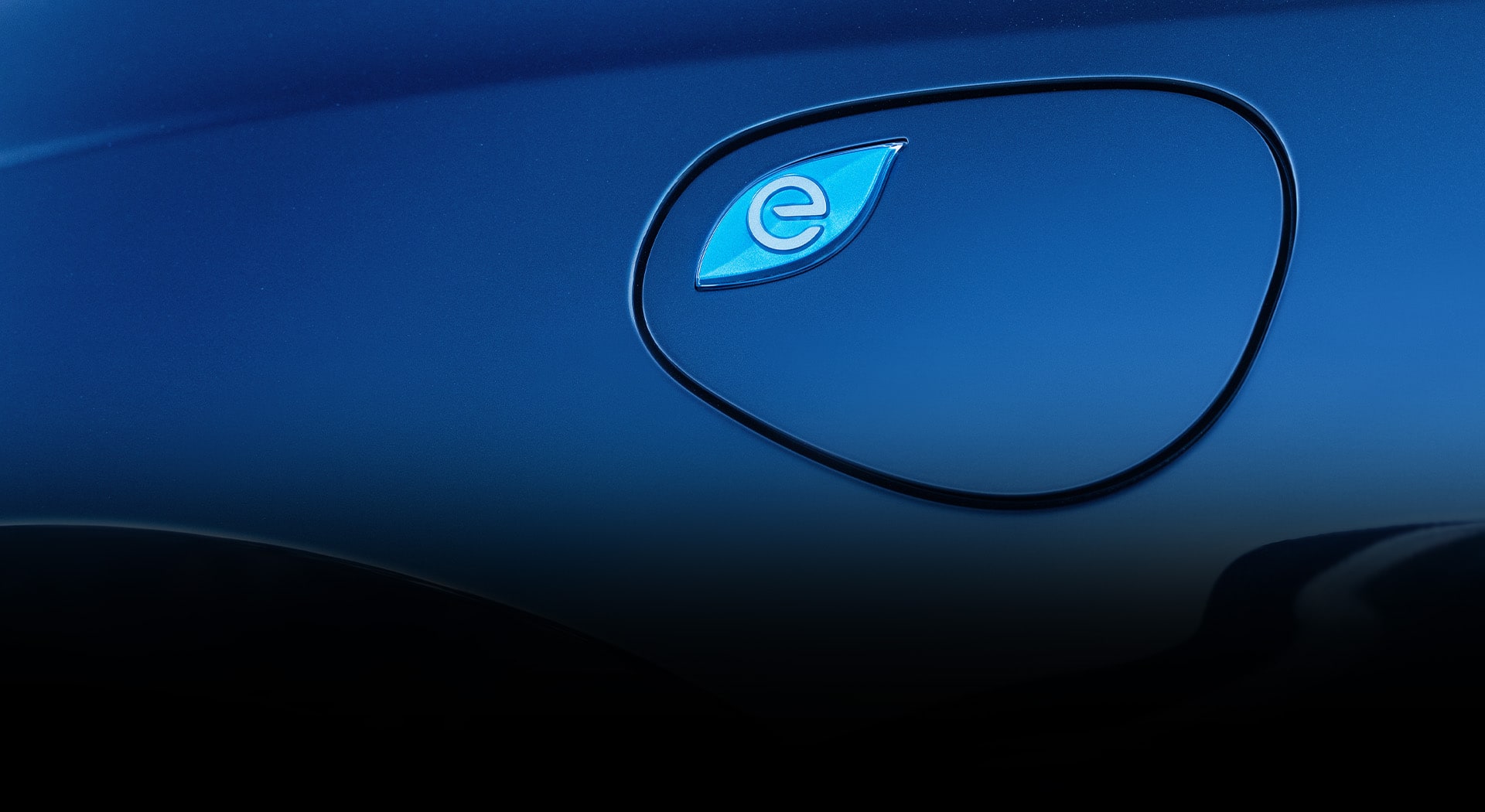 A close-up of the charging port cover on a blue 2025 Chrysler Pacifica Plug-in Hybrid.